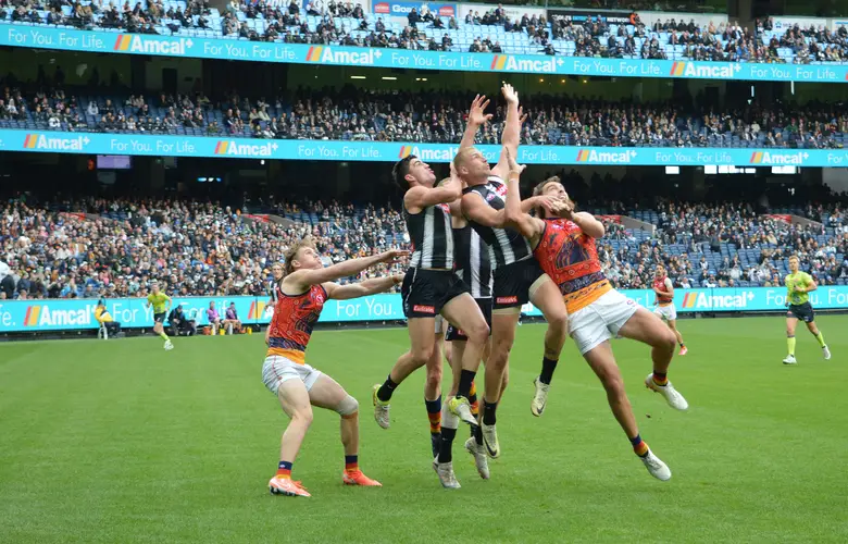 Collingwood and Adelaide players leap together for a pack mark at the MCG, 2025
